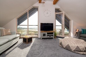 A modern living room with a television, sofa, and a view of the outdoors.