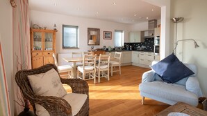 Una sala de estar acogedora con una silla de mimbre, un sofá a rayas y una zona de comedor con una mesa y sillas de madera.