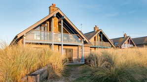Una casa costera con techo inclinado, ventanas amplias y chimenea de piedra.