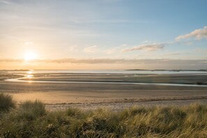 A coastal landscape with a wide sandy beach and gentle waves.