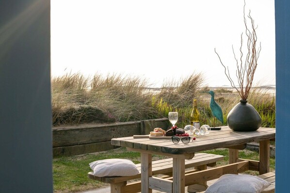A wooden picnic table with a bottle of wine, glasses, and food items.