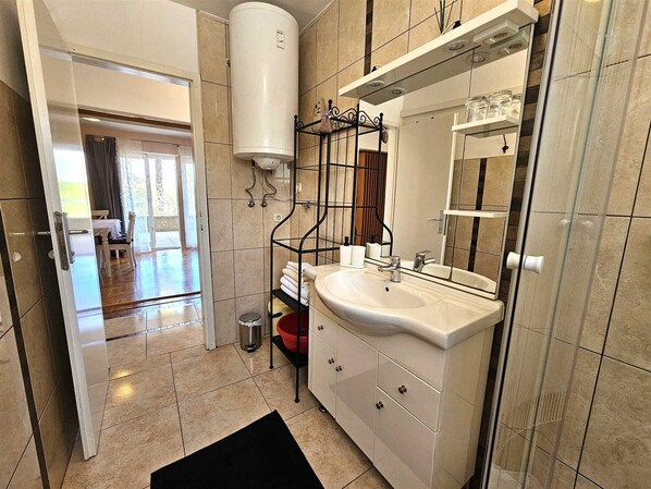 Un baño moderno con un lavamanos grande, un espejo y un perchero para toallas.