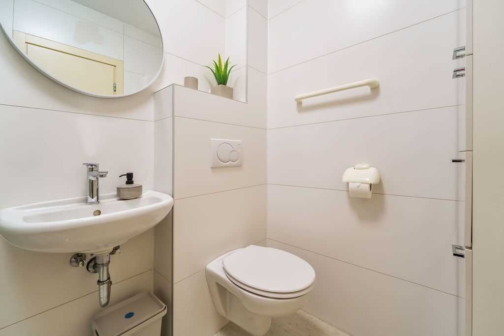 A bathroom with a sink, toilet, mirror, and towel rack.