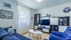 A living room with a sofa, a coffee table, a TV, a cabinet, and a bookshelf. - Apartment Jelena Punat | 300m from Beach & near Medane Beach (Punat)