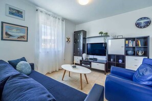Un saló amb un sofà, una taula de centre, una televisió, un armari i una prestatgeria.