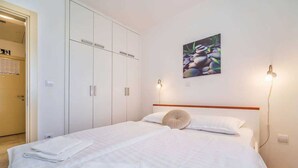 A hotel room with a bed, white wardrobe, and a wall-mounted picture. - Apartment Jelena Punat | 300m from Beach & near Medane Beach (Punat)