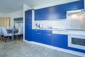 A modern kitchen with blue cabinets, a coffee maker, and a dishwasher.