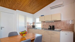 A compact kitchen with a wooden ceiling, white cabinets, a microwave, and a small refrigerator.
