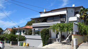 A modern two-story house with a flat roof, large windows, and a satellite dish.