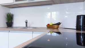 Une cuisine moderne équipée d’une cuisinière intégrée, d’un évier et d’un plan de travail sur lequel se trouve un panier rempli de fruits et de légumes.