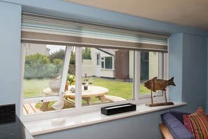 A room with a large window, a wooden table, and a bench. - Tyn Lon: Traditional Anglesey holiday cottage, 4 guests (Rhosneigr)