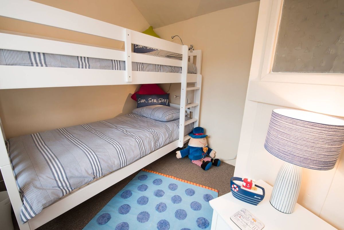 A bunk bed with striped bedding, a small rug, a lamp, and a toy on the floor.
