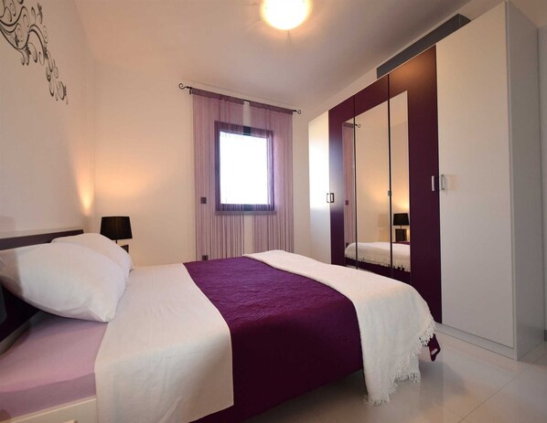 Una camera da letto con un letto, un comodino, una finestra con tende e un armadio con specchio.