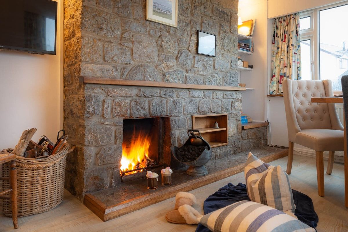 A cozy room with a stone fireplace, a television mounted on the wall, and a comfortable chair.