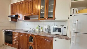 Eine Küche mit Holzausstattung, einer Mikrowelle, einer Kaffeemaschine und einem Kühlschrank.