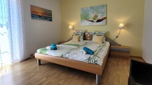 Ein Schlafzimmer mit einem Bett, zwei Nachttischen, zwei Wandleuchten und einem Fenster mit Vorhängen.