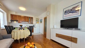 Ein modernes Wohnzimmer mit Essbereich, Küche und Fernseher auf einem weißen Schrank.