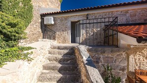 A stone staircase leading to a building with a tiled roof and a metal railing.