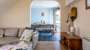 A cozy living room with a sofa, a dining table, and a kitchen area visible through an archway.