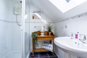 A bathroom with a shower, a sink, a wooden vanity, and a potted plant. - The Granary: A two bed, pet-friendly holiday cottage (Ty Croes)