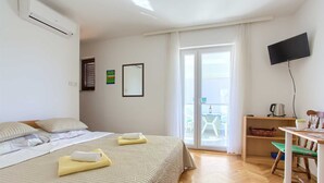 A hotel room with a bed, a desk, a chair, a TV, and a balcony with a view.