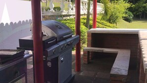 A barbecue grill and a brick oven in an outdoor setting with a garden and white fence in the background. - Villa for rent in Cerritos Pereira (Pereira)