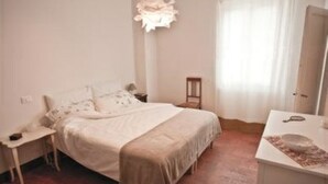 Un dormitorio con cama, mesita de noche y pequeño mueble auxiliar.