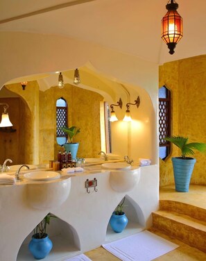 A bathroom with two sinks, a mirror, and a potted plant.