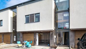 Una moderna casa a schiera con garage, area salotto esterna e una scala visibile che porta all'ingresso.