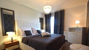 Et pænt opredt soveværelse med en stor seng, et natbord med lampe, et klædeskab og en lysekrone.