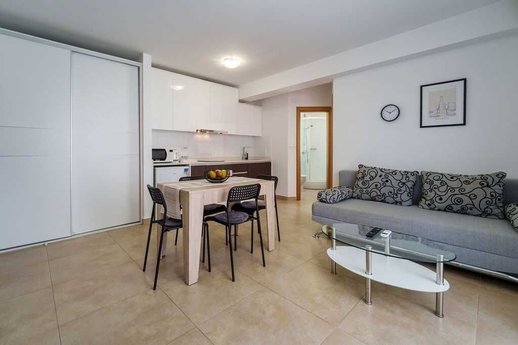 Un espace de vie compact comprenant une kitchenette, un coin repas et un canapé.