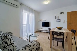 A living room with a sofa, a glass coffee table, a TV, and a dining area with chairs and a table. - Apartment Nino 3 on the first floor (Malinska)