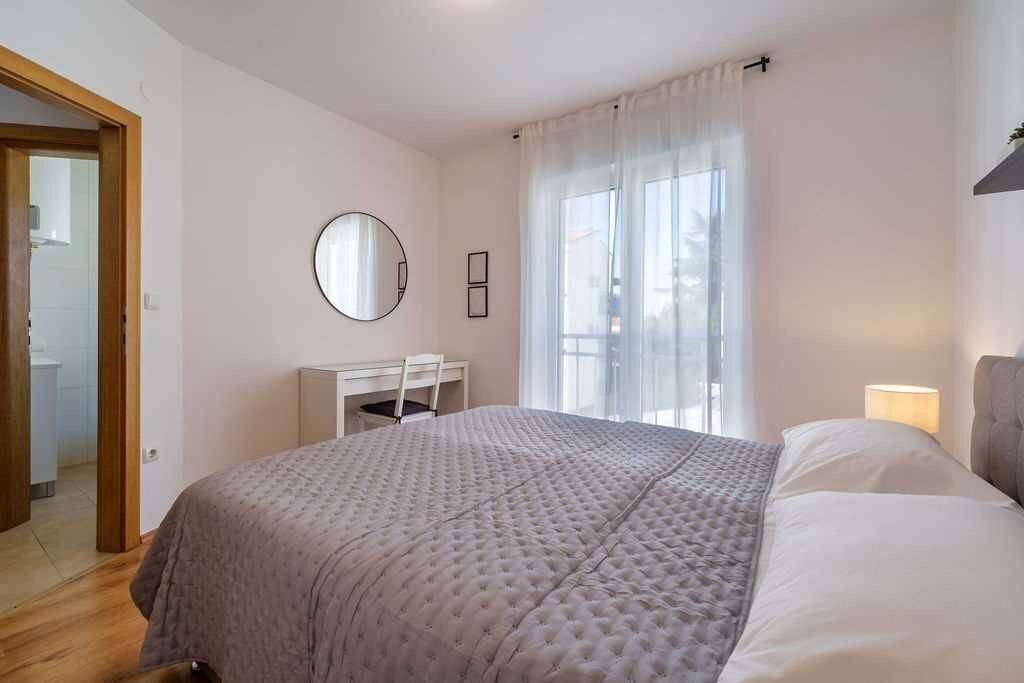Un dormitorio con cama, escritorio y ventana con cortinas.