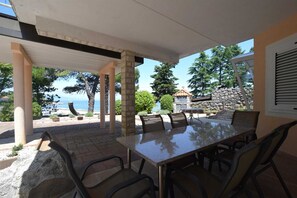 An outdoor patio with a table and chairs, overlooking a scenic view of the sea and trees. - Apartment Frane 3 with Seaview (Vantačići)