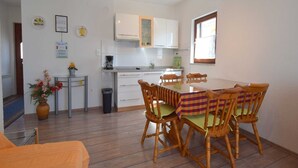 Ett kompakt bostadsutrymme med en matplats, ett litet kök och en liten sittgrupp.