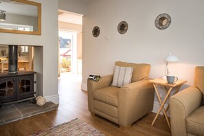 Un salon chaleureux avec un canapé, une petite table sur laquelle se trouve une lampe, et une cheminée.