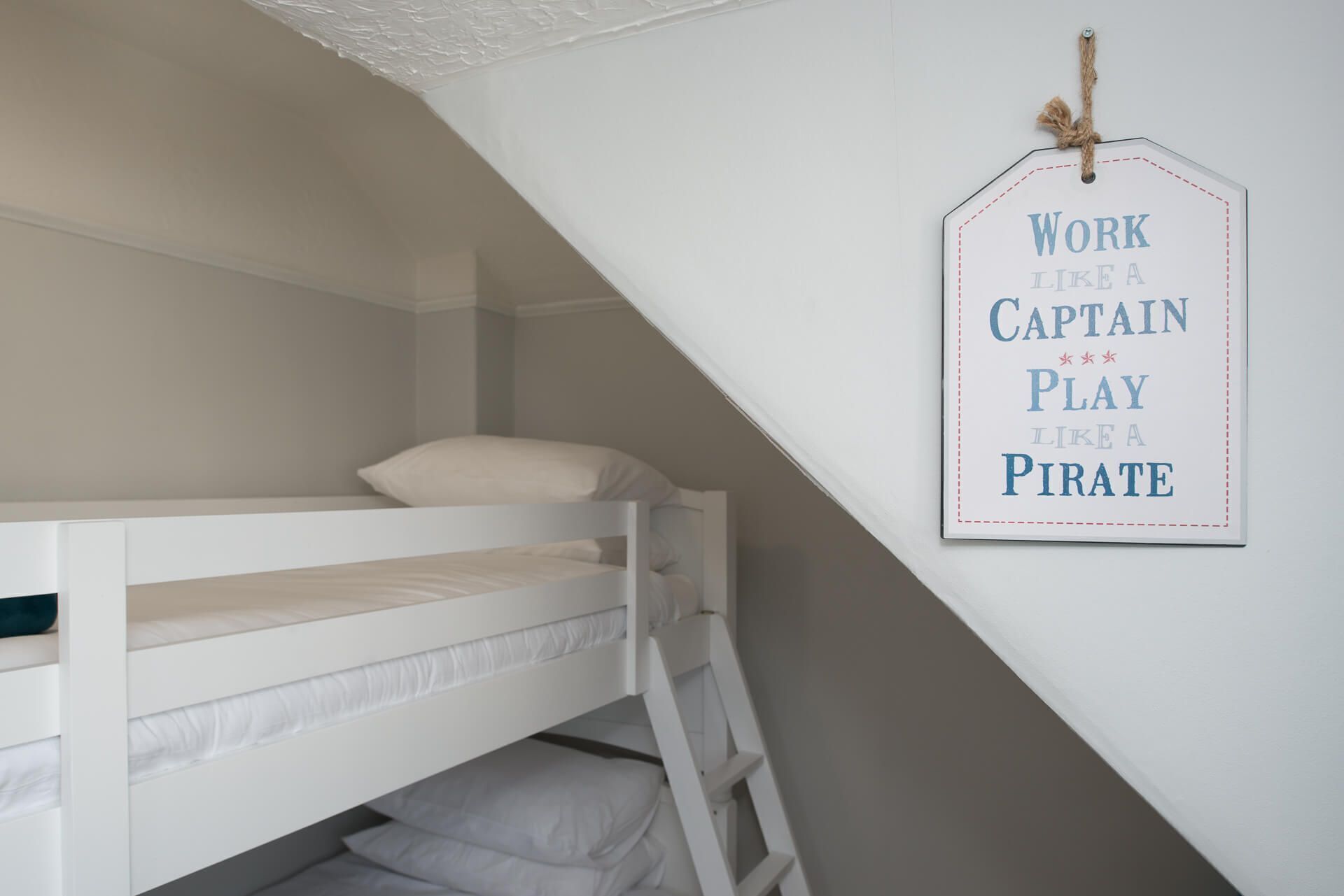 Een stapelbed in een kamer met een schuine plafond en een motiverende poster aan de muur.