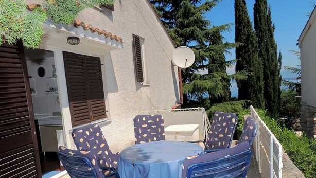 Une terrasse extérieure avec une table ronde et des chaises, une antenne parabolique et une vue sur la mer.
