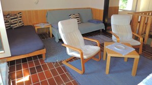 Une pièce confortable avec un canapé, deux fauteuils, une petite table et une fenêtre.
