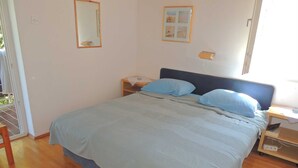 Une chambre à coucher avec un lit, une table de chevet, une commode, un miroir et un tableau accroché au mur.