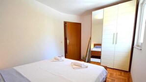 Une chambre à coucher avec un lit, une armoire et un miroir qui reflète la pièce.