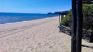 Une plage avec une structure en bois, un ciel bleu clair et une mer calme.