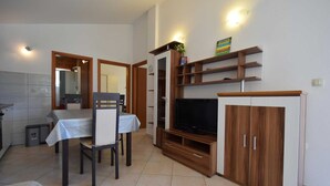 A compact living space with a dining area, a TV, and built-in wooden shelves.