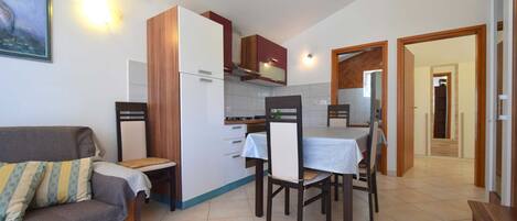 A compact living space with a sofa, dining table, chairs, a kitchenette, and a small kitchen.