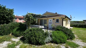 A two-story house with a tiled roof, a satellite dish, and a garden with various shrubs and flowers.
