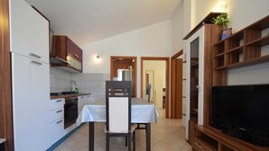 A compact kitchen with a dining table and chairs, a television, and wooden cabinets.