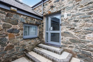 Un bâtiment en pierre doté d’une porte et d’un escalier menant à un porche.