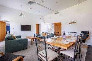 Un espace repas moderne avec une table en bois, des chaises et un téléviseur fixé au mur.