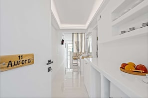 Enter room 11 Aurora, featuring a sleek, white interior and a breakfast bar with a fruit basket.
