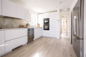 Enjoy cooking in this well-lit kitchen with white cabinetry, a refrigerator, and oven.